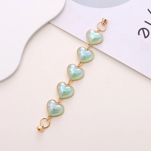Close-up of heart-shaped light green beaded phone strap with iridescent gold trim edges