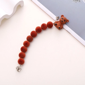 Detail of plush orange bear phone strap with fuzzy balls and silver metal hardware