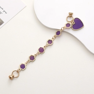 Détail de chaîne en métal doré avec perles hexagonales violettes et pendentif cœur