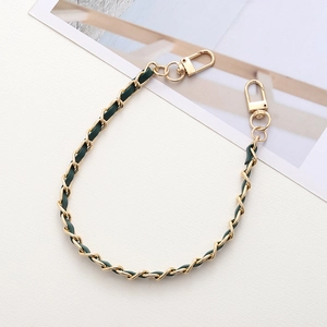 Detail of light gold metal chain woven with dark green leather and lobster clasps