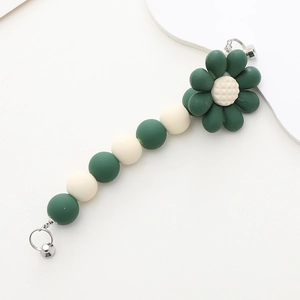 Detail showing matte dark green and beige acrylic beads with a white flower charm
