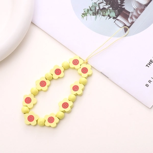 Close-up of yellow wooden flower beads and round pearls on a handmade phone wrist strap