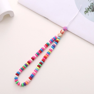 Macro detail of colorful polymer clay beads phone strap with floral charms on white background
