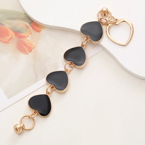 Détail d'une chaîne dorée avec quatre pendentifs cœur en émail noir et charme ajouré