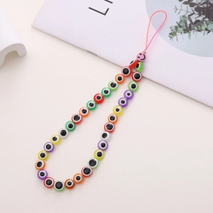 Detail shot of colorful Evil Eye beads and pink smiley face on a handmade phone strap