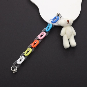 Detail of colorful acrylic chain with a small white plush bear and silver metal ring