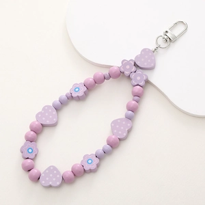 Detail of purple wooden beads pendant with floral and heart patterns on white background
