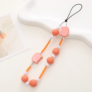 Close-up of beaded phone charm with pink pig motifs, orange beads and white pearls