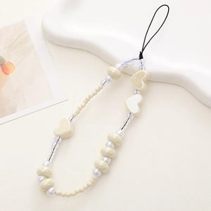 Detail of handmade cream-colored beaded phone strap with heart-shaped and round pearls
