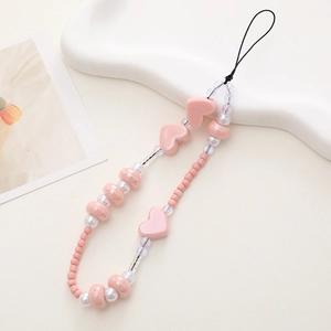 Close-up of pink heart-shaped beads and white pearls on a stylish handmade phone strap