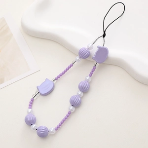 Detail view of purple beaded phone wrist strap with cat motifs on a white tray