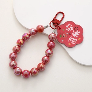 Detail of red beaded phone charm with Lucky Apple pendant and lobster clasp