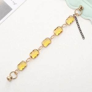Detailed macro view of amber rectangular crystals on a gold alloy bracelet with magnetic clasp