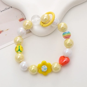 Colorful handmade beaded phone strap with yellow flower and red heart charms on white tray