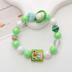 Detail of beaded mobile phone strap featuring green beads and a funny face charm