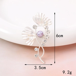 Detail view of silver floral brooch with purple pearl and rhinestones 6cm by 3.5cm