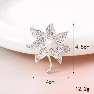 Detailed macro view of rhinestone flower brooch with pearl center and silver base