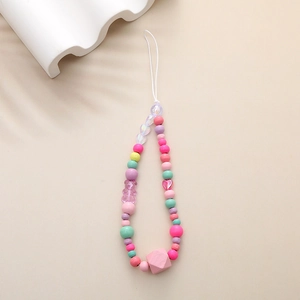 Detail of colorful beaded phone strap with cute bear and heart charms on beige background