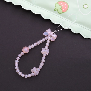 Détail de la dragonne de téléphone en perles roses nacrées avec nœud et papillon