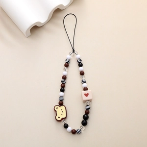 Detail of beaded phone strap featuring a yellow bear charm and heart cube bead