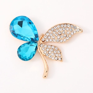 Golden butterfly brooch with blue teardrop gems and white rhinestones on a white background