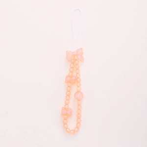 Chaîne de téléphone perlée orange avec pendentifs ours et nœud sur un fond beige doux