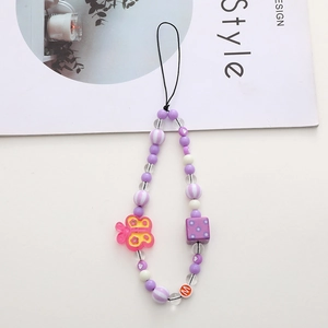 Purple beaded phone strap with pink butterfly charm and checkered bead on stylish magazine