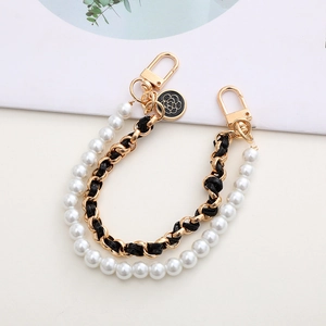 Détail de la double chaîne de luxe en perles et cuir doré avec pendentif camélia