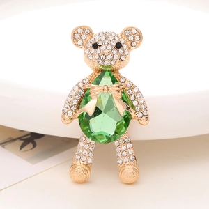 Detailed close-up of a luxury gold bear pendant featuring a green teardrop gemstone