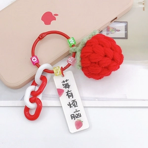 Detail of handmade crochet strawberry keychain with red beads and metal ring accessory