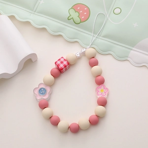 Détail de la lanière de téléphone perlée rose et blanche avec des perles à carreaux