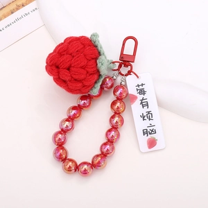 Detailed view of a handmade crochet strawberry pendant with metallic beads and red hook
