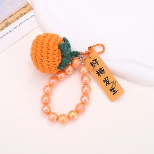 Handmade knitted persimmon keychain with orange beads and lucky charm tag