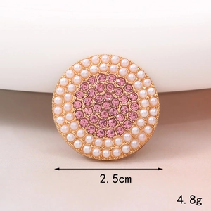 Dettaglio di un ciondolo dorato di 2,5 cm con strass rosa e perle sintetiche