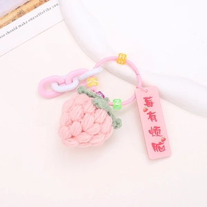 Close-up of pink handmade knitted strawberry pendant with beaded chain and charm