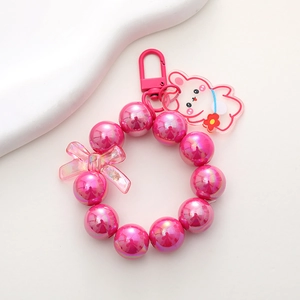Detail of pink pearlescent beaded keychain with acrylic rabbit and butterfly charms