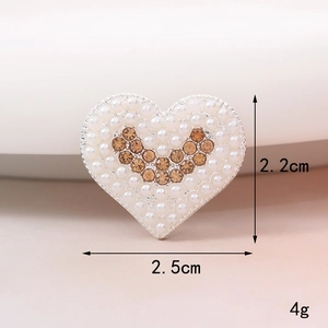 Dettaglio di ciondolo a cuore con perle bianche e cristalli ambra con misura 2,5 cm