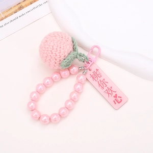Close-up of pink crochet peach keychain with colorful beads and peach-themed tag