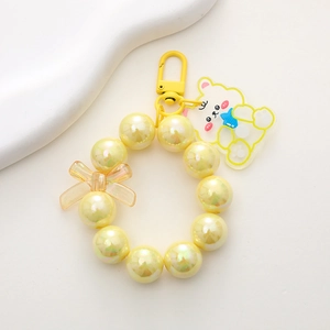Close-up of iridescent yellow beaded charm with a cute bear pendant and a metal clip