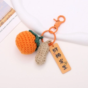 Handmade crochet persimmon and peanut keychain with orange clasp on minimal background