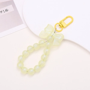 Detail view of a pale yellow beaded keychain with a resin bow and matching lobster clasp