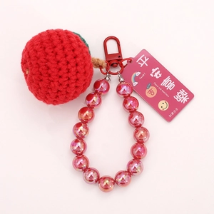 Handmade knitted apple keychain with pink beads and a red metal carabiner on a white background