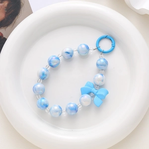 Détail de la dragonne de téléphone en perles marbrées bleues avec nœud mat et fermoir