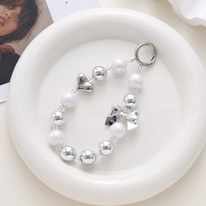 Bijou de téléphone en perles avec cœur argenté et nœud sur plateau blanc