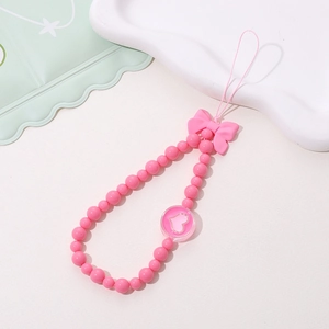 Detail of pink beaded phone strap with bowknot decoration and heart pendant