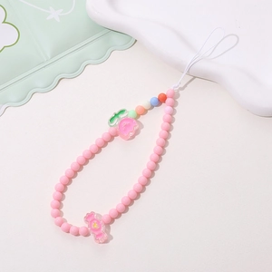 Detailed view of pink beaded phone strap with peach pendant and candy charm accessories