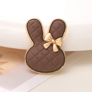 Detail eines braunen Plaid-Hasen-DIY-Accessoires mit goldener Metallschleife auf weißem Grund