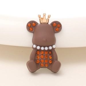 Détail du charm ours marron mat avec couronne dorée, collier de perles et strass orange