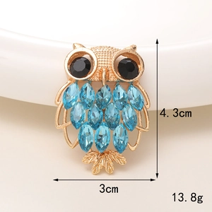 Detailed view of owl charm accessory with blue crystals and gold-tone metal frame