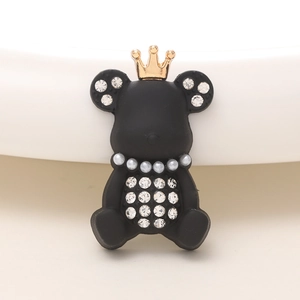 Détail d'une breloque ours noir mat avec couronne dorée et strass blancs étincelants